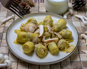 Plate of cooked artichokes with fresh mushrooms served on a rustic background, perfect for healthy cooking and autumn cuisine