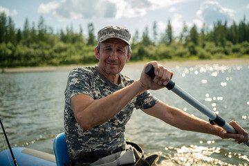 An elderly fisherman rows with an oar and looks ahead