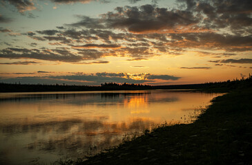 Golden sunset with clouds near evening lake