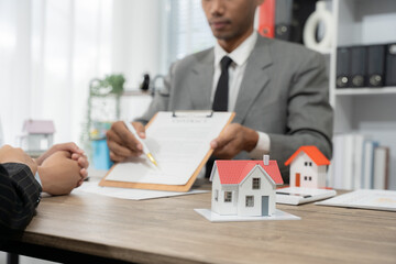Real estate agent presenting house models to satisfied client giving a thumbs up during a...