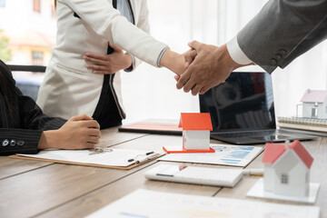 Real estate agent presenting house models to satisfied client giving a thumbs up during a productive meeting in the office, highlighting successful discussions about property investment