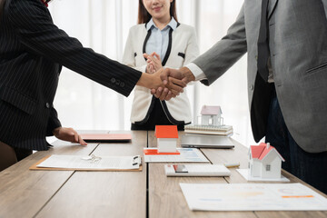 Real estate agent presenting house models to satisfied client giving a thumbs up during a productive meeting in the office, highlighting successful discussions about property investment