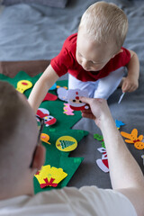 Fototapeta premium Little child decorating with his father the toy Christmas tree. Educational games for children.
