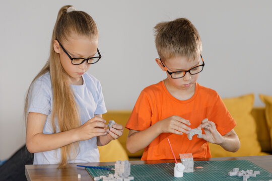 Boy and girl in glasses assembling constructor at school desk. Educational STEM activity for children developing creativity, teamwork, and problem-solving skills.