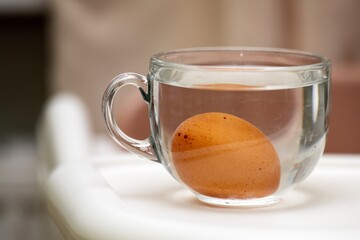 hard-boiled egg cooling in a transparent glass mug filled with water