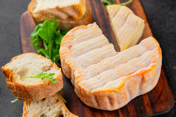 Washed rind cheese soft cheese with orange rind munster french cheese tasty snack fresh delicious gourmet food background on the table rustic top view copy space