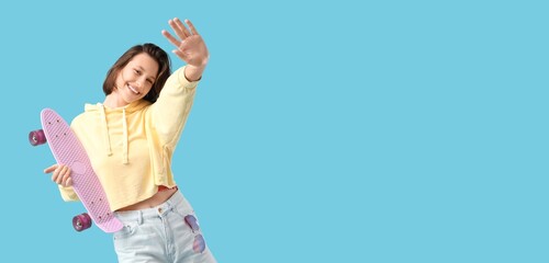 Young woman with skateboard dancing on blue background with space for text © Pixel-Shot