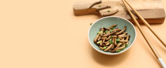 Bowl with fried maggots and green onion on beige background with space for text