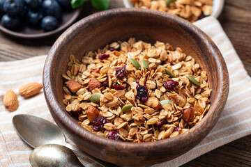 Homemade granola with dried cranberries, pumpkin seeds and almonds in wooden bowl