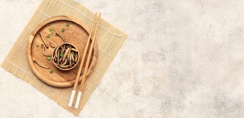 Wooden bowl with fried maggots and chopsticks on light background with space for text