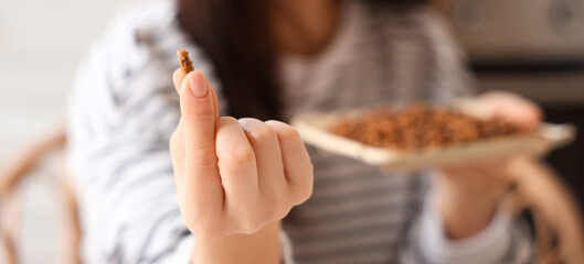 Young woman with fried insect in kitchen, closeup