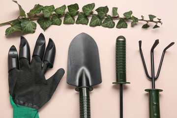 Set of gardening tools, glove and ivy branch with leaves on beige background
