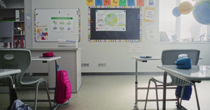 Interior of Modern Empty Primary School Classroom with Desks for Students, Chalkboard, Hanging Models of Solar System and Colorful Posters. Creative Space for Children Studying and Education Process.
