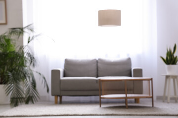 Interior of stylish living room with grey sofa, table and light curtains