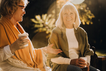 Elderly women enjoying coffee and conversation in autumn sunlight
