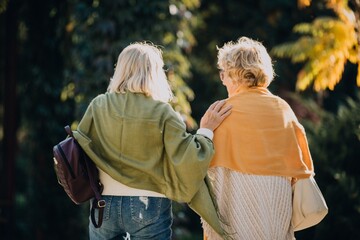 Two senior women walking together in a park, showing support and companionship