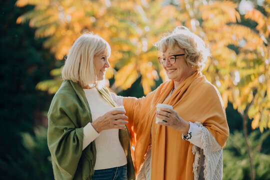 Elderly women enjoying coffee and conversation in autumn park