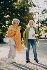 Two senior women holding hands and walking in the park