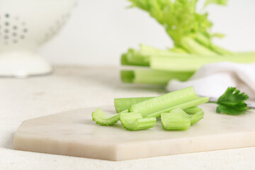 Board with cut fresh green celery on white background