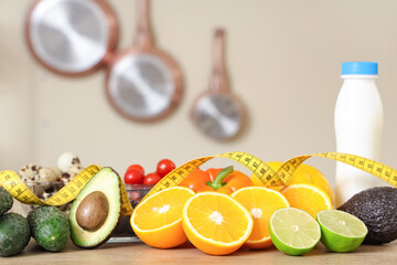 Healthy food with tape measure on table in kitchen, closeup. Diet concept