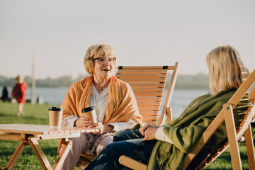 Elderly women enjoying coffee and conversation by the river