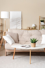 Interior of beautiful living room with comfortable sofa, coffee table, houseplant and pillows, closeup