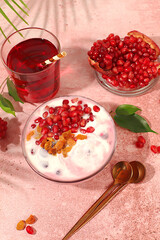 Pomegranate yogurt bowl with pomegranate pieces, raisins fresh cream for healthy eating and natural juice. Healthy breakfast with ingredients, kitchen background, Natural nutrition and diet concept