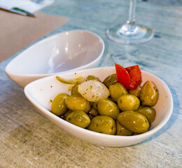Green olives, spices and onions for an aperitif, in a heart-shaped bowl