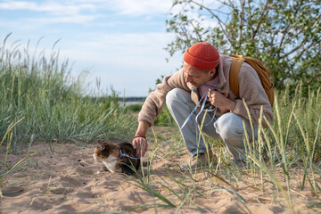 Caring man stroke petting cat on beach helping overcome fear of unfamiliar place. Cautious pet trust to owner, pet owner reassuring feline, human animal bond, nervous scared animal in new surroundings