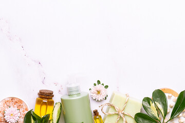 Skin care organic products such as shower gel or cream, or lotion and hand made soap with avocado oil on white marble background decorated with fresh avocado slices and palm leaves.