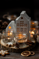 Creating holiday mood, festive atmosphere at home. Christmas spirit, atmospheric composition with handmade aroma candles made from simple glass jars, homemade gingerbread cookies, anise cinnamon scent