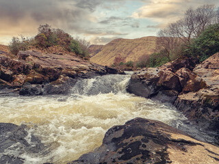 Small and powerful river Erriff in county Galway, Ireland. Connemara area. Rough stream with rocks, waterfall and mountains in the background. Irish nature scene. Popular travel area.