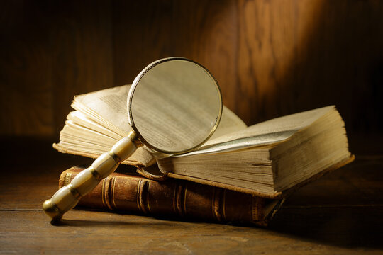 Open antique book with magnifying glass. Concept for learn history, investigation, find artifacts.  - Powered by Adobe