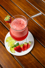 Healthy detox berry smoothie with fresh ingredients such as strawberry, watermelon, and lemon, a refreshing vegan drink for a healthy lifestyle and diet, served in a glass on a wooden table.