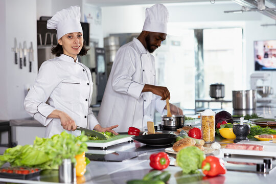 In a professional kitchen, chef preparing gourmet meals by using cutting boards and chopping ingredients. Expert cooking with fresh produce, doing food prep for tasty dishes, gastronomy. - Powered by Adobe