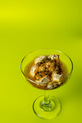 Yellow fruit dessert with fresh ingredients such as passion fruit, cookies, and cream, served in a glass on a yellow table.