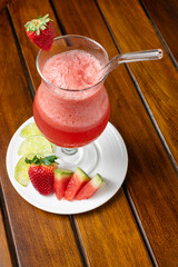 Healthy detox berry smoothie with fresh ingredients such as strawberry, watermelon, and lemon, a refreshing vegan drink for a healthy lifestyle and diet, served in a glass on a wooden table.