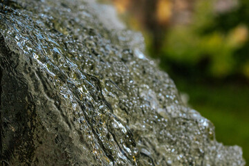 Close-up view of water cascading over moss-covered rocks, highlighting textures, movement, and natural details.