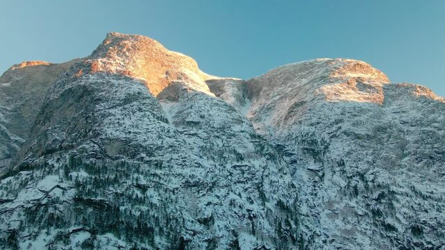 aerial view captures the majestic snow covered mountains bathed in the warm glow of sunrise or sunset, highlighting the rugged beauty of the Eresfjord or Eikesdalen region.