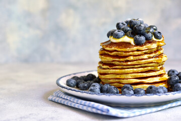 Stack of fresh hot banana pancakes with maple syrup and blueberries for a breakfast.