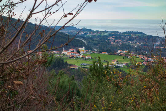 Vista de un pueblo desde la monta&ntilde;a con ramas en primer plano