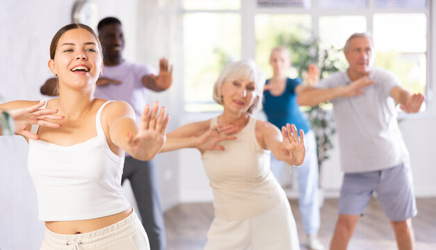 In fitness studio, youthful female coach is leading class for seniors. Instructor is teaching older students fundamental steps of hip hop dance in dance lesson - Powered by Adobe