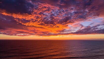 a vibrant sunset sky with dramatic clouds illuminated in fiery tones of orange and purple casting a warm glow over the endless ocean horizon