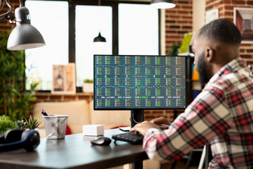 Focused entrepreneur working from home, analyzing stock market and planning profitable investment strategies for startup business. Man seated at desk reviewing forex trading trends with concentration.