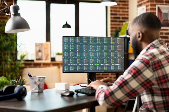 Focused entrepreneur working from home, analyzing stock market and planning profitable investment strategies for startup business. Man seated at desk reviewing forex trading trends with concentration.