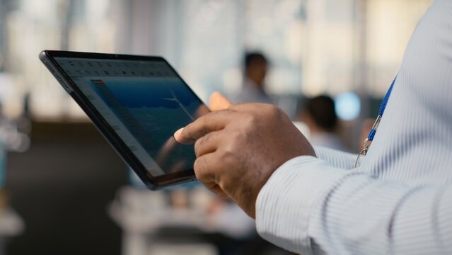 Close up of engineer in office using tablet to work on wind turbine CAD design, doing sustainable energy research. Worker doing digital modeling of wind energy generator gear on device, camera B
