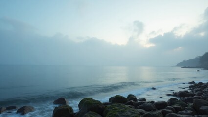 A tranquil coastal scene at dawn, showcasing a misty expanse of sea and shore.