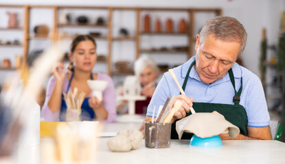male potter gives clay billet shape of vase