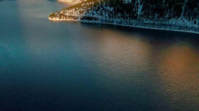 This drone footage shows beauty of a serene winter fjord, nestled amidst snow capped mountains and pristine waters, capturing the tranquil essence of Eikesdalen or Eresfjord in Norway.
