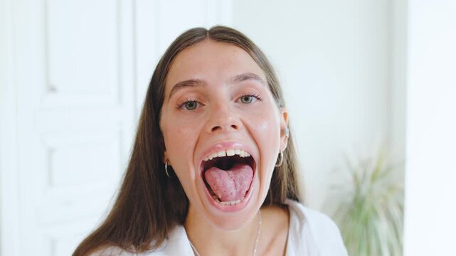 Speech therapist conducts a session with a young woman practicing tongue exercises in a bright and airy room to improve communication skills